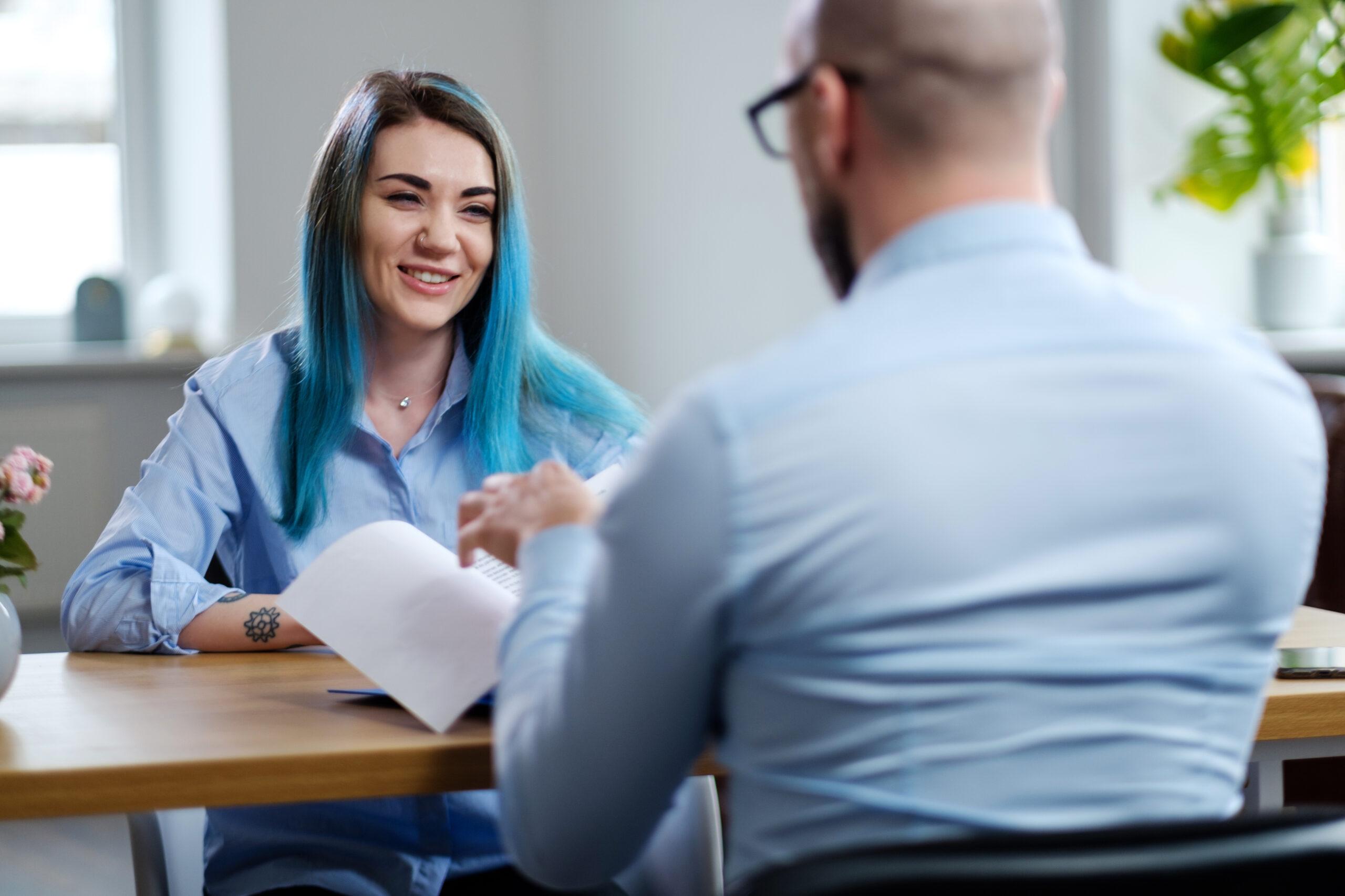 An image of a young woman being interviewed for a job in an office setting.